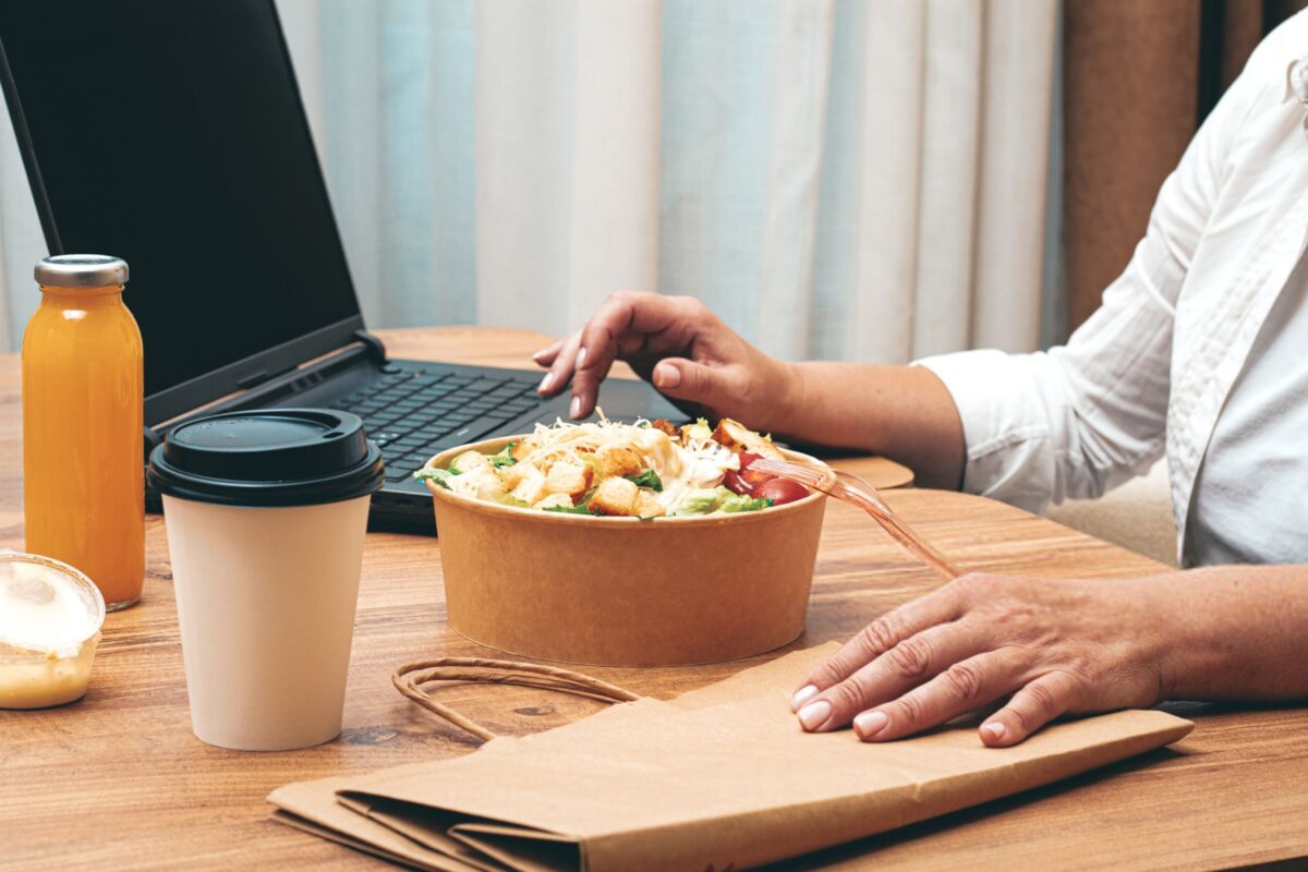 ظرف غذای بیرون‌بر بازشده روی میز در یک محیط کاری مدرن.